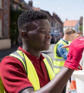 Young person paints a fence, volunteer